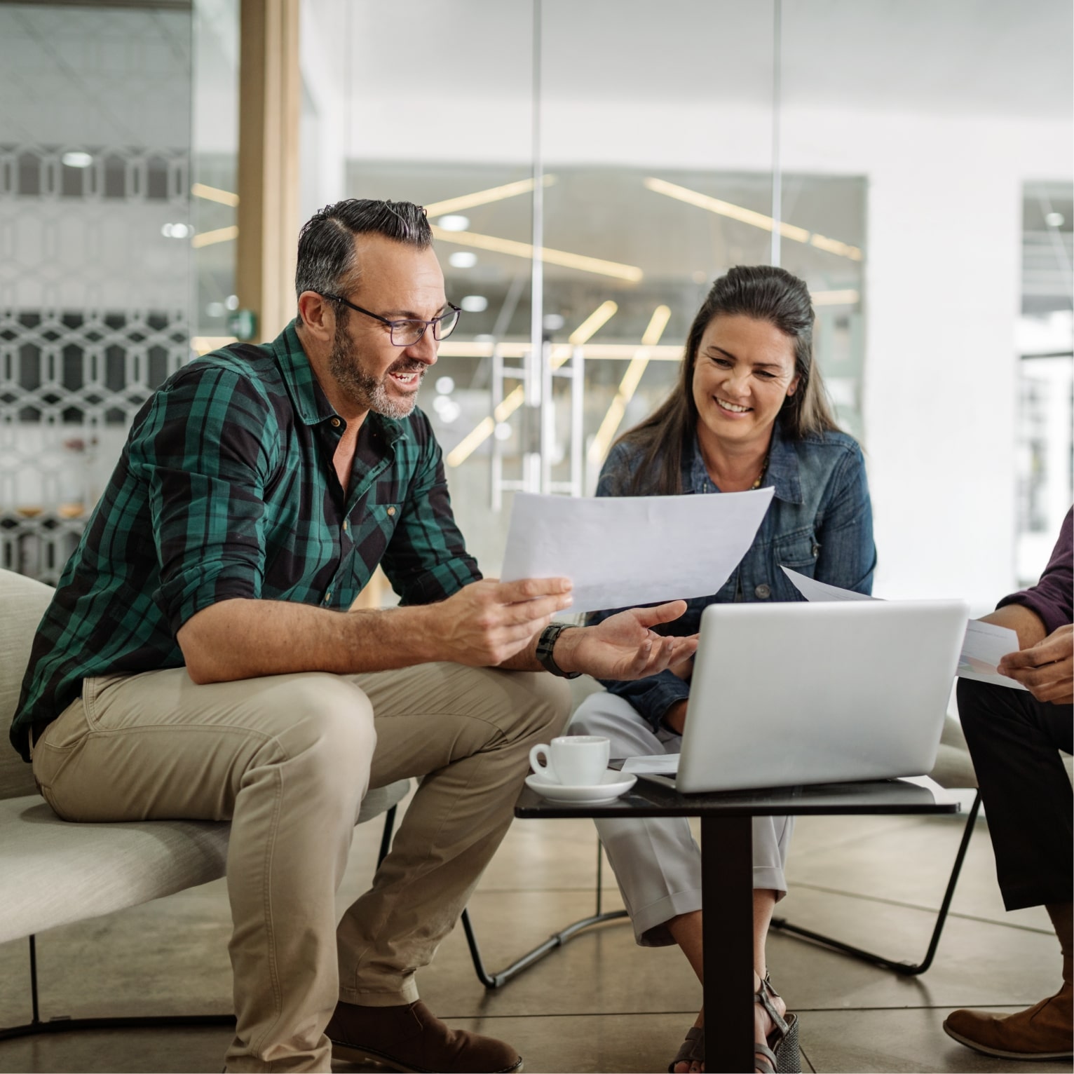 people reviewing documents in front of a laptop